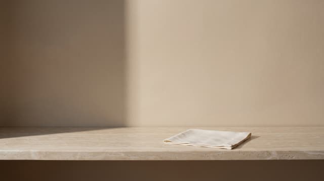 Morning light on a travertine shelf with a folded linen cloth