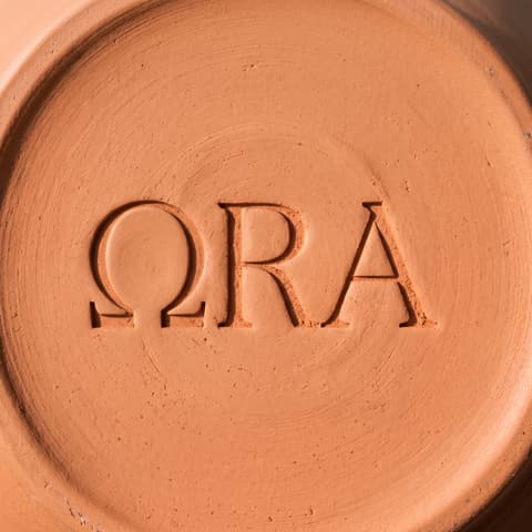 The ora wordmark on the base of a terracotta vessel